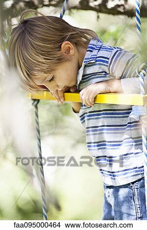 Picture - Little boy standing on swing. Fotosearch