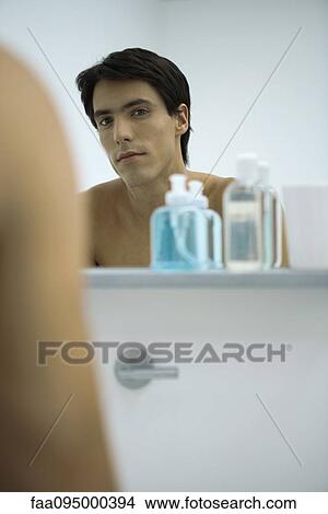 Picture - Man looking at self in mirror. Fotosearch