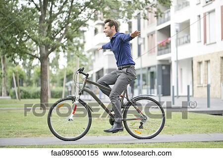 Man riding bicycle with arms outstretched View Large Photo Image Stock Photography - Man riding bicycle with arms outstretched. Fotosearch