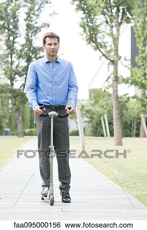 Man riding push scooter View Large Photo Image Stock Photograph - Man riding push scooter. Fotosearch