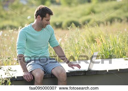 Stock Photo - Man using laptop computer outdoors. Fotosearch