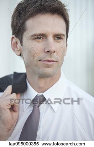 Stock Photography - Mid-adult businessman carrying suit jacket over shoulder looking away in contemplation, portrait. Fotosearch