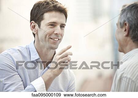 Stock Photo - Mid-adult man talking with friend. Fotosearch