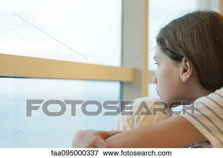 Preteen girl hugging knees, looking out window View Large Photo Image Stock Photo - Preteen girl hugging knees, looking out window. Fotosearch