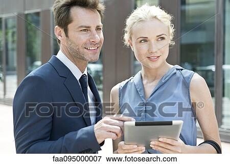 Stock Photo - Real estate agent with digital tablet showing property to potential buyer. Fotosearch