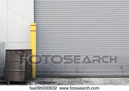 Stock Image - Rusty barrels by closed loading dock. Fotosearch