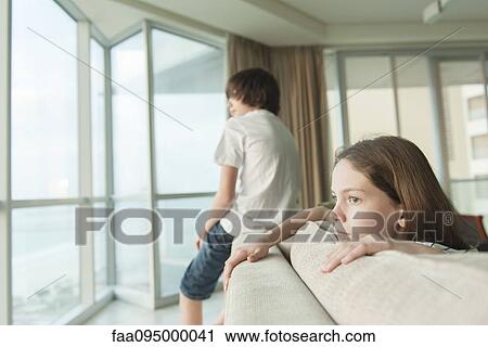 Siblings sitting on sofa, looking out window View Large Photo Image Stock Image - Siblings sitting on sofa, looking out window. Fotosearch