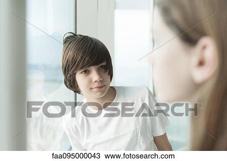 Stock Image - Teenage boy leaning against window. Fotosearch