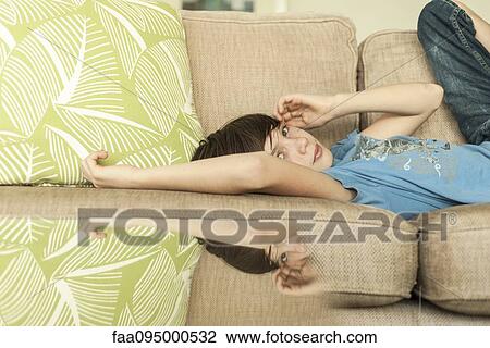 Stock Image - Teenage boy lying on sofa. Fotosearch