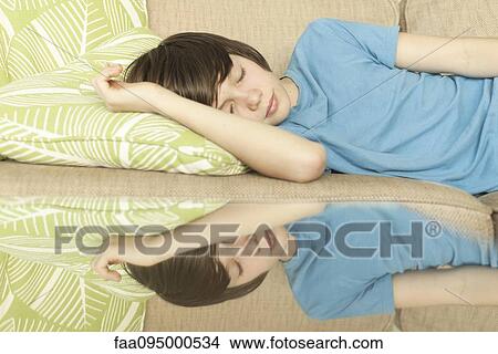 Picture - Teenage boy napping on sofa. Fotosearch