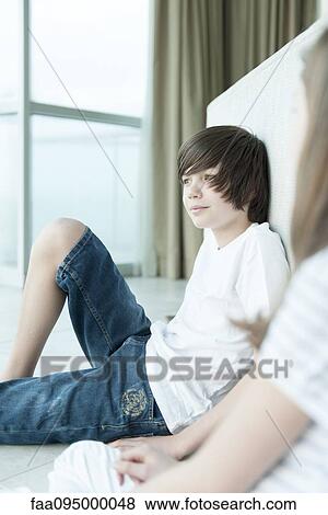 Teenage boy sitting on floor looking out window View Large Photo Image Stock Photo - Teenage boy sitting on floor looking out window. Fotosearch