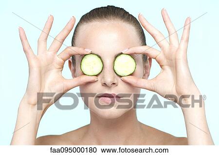 Woman holding cucumber slices on eyes View Large Photo Image Stock Image - Woman holding cucumber slices on eyes. Fotosearch