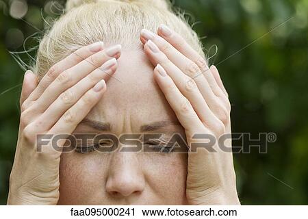 Stock Image - Woman holding head with distressed expression. Fotosearch