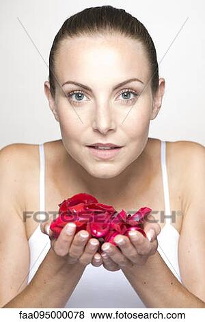 Stock Photo - Woman holding rose petals in cupped hands, portrait. Fotosearch