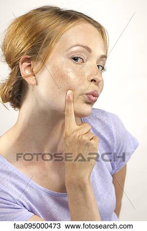 Stock Image - Woman puckering lips and pointing to cheek, portrait. Fotosearch