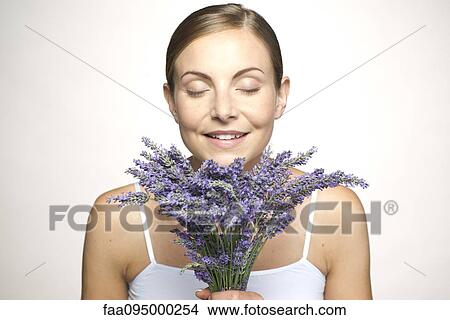 Picture - Woman smelling bouquet of fresh lavender with eyes closed. Fotosearch