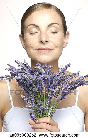 Stock Image - Woman smelling bouquet of fresh lavender with eyes closed. Fotosearch