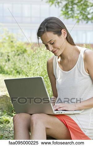 Stock Photography - Woman using laptop computer outdoors. Fotosearch