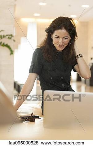 Stock Photo - Woman using laptop computer, smiling. Fotosearch