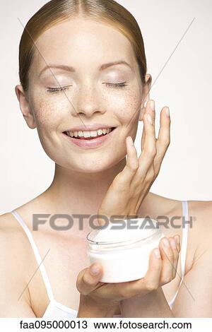 Youn woman moisturizing face with eyes closed View Large Photo Image Stock Image - Youn woman moisturizing face with eyes closed. Fotosearch