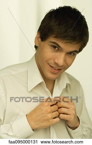 Young man buttoning shirt, smiling, portrait View Large Photo Image Stock Image - Young man buttoning shirt, smiling, portrait. Fotosearch