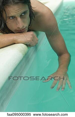 Young man lying beside swimming pool, dangling arm in water View Large Photo Image Stock Photography - Young man lying beside swimming pool, dangling arm in water. Fotosearch