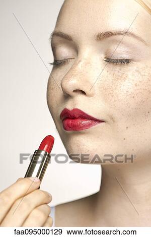 Young woman applying lipstick, eyes closed View Large Photo Image Stock Photo - Young woman applying lipstick, eyes closed. Fotosearch