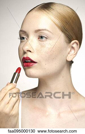Young woman applying lipstick, portrait View Large Photo Image Stock Image - Young woman applying lipstick, portrait. Fotosearch