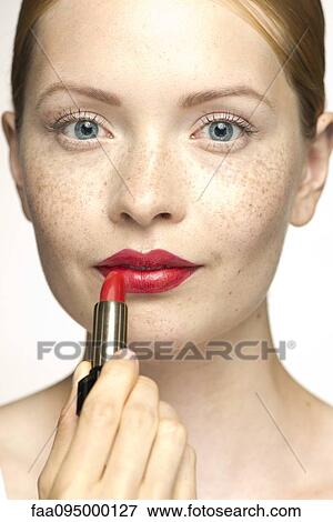 Stock Photo - Young woman applying lipstick, portrait. Fotosearch