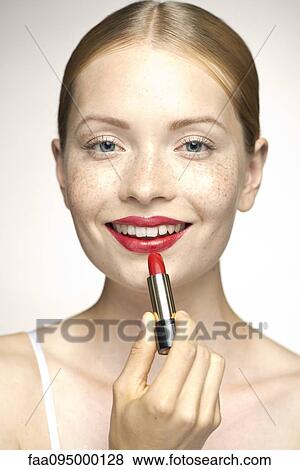 Stock Photo - Young woman applying lipstick, portrait. Fotosearch