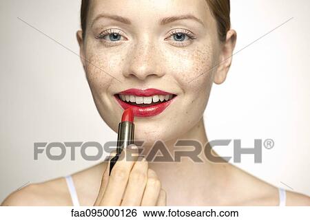 Young woman applying lipstick, portrait View Large Photo Image Stock Photograph - Young woman applying lipstick, portrait. Fotosearch