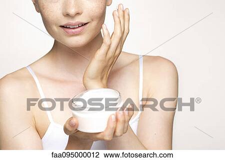 Young woman applying moisturizer to face, portrait View Large Photo Image Stock Image - Young woman applying moisturizer to face, portrait. Fotosearch