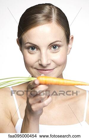 Young woman balancing carrot on hand, portrait View Large Photo Image Picture - Young woman balancing carrot on hand, portrait. Fotosearch