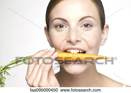 Young woman biting into carrot, portrait View Large Photo Image Stock Image - Young woman biting into carrot, portrait. Fotosearch