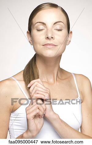 Young woman holding ends of ponytail, eyes closed, portrait View Large Photo Image Stock Photo - Young woman holding ends of ponytail, eyes closed, portrait. Fotosearch