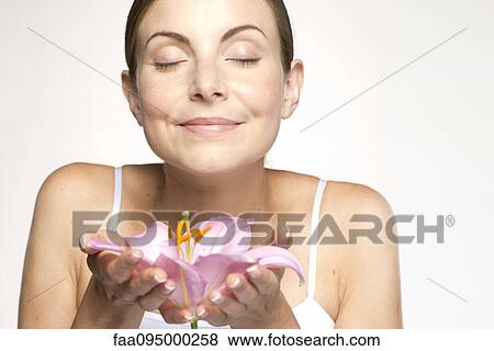 Young woman holding lily in cupped hands, eyes closed View Large Photo Image Stock Photo - Young woman holding lily in cupped hands, eyes closed. Fotosearch