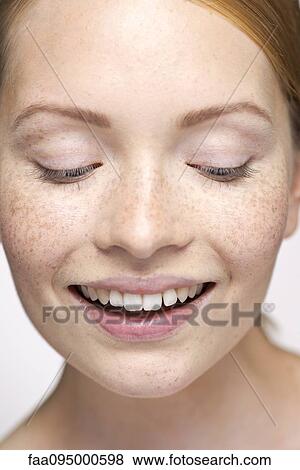 Stock Photo - Young woman looking down, smiling, close-up portrait. Fotosearch