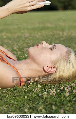 Young woman lying on grass using smartphone View Large Photo Image Stock Image - Young woman lying on grass using smartphone. Fotosearch