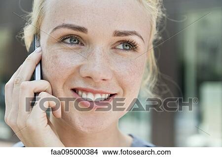 Picture - Young woman making phone call using smartphone. Fotosearch