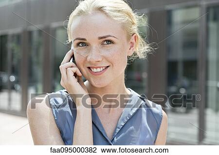 Stock Image - Young woman making phone call using smartphone. Fotosearch