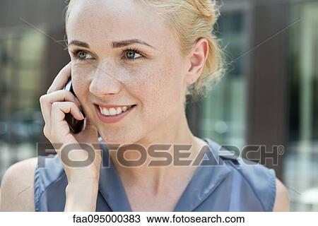 Stock Image - Young woman making phone call using smartphone. Fotosearch