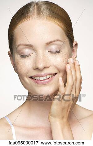 Young woman moisturizing face, eyes closed View Large Photo Image Stock Photo - Young woman moisturizing face, eyes closed. Fotosearch