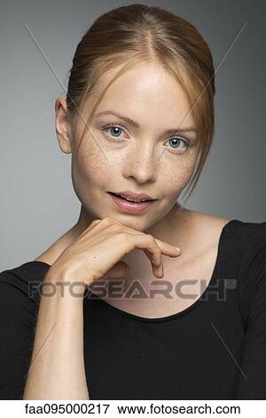 Young woman sitting with hand under chin, portrait View Large Photo Image Stock Photo - Young woman sitting with hand under chin, portrait. Fotosearch