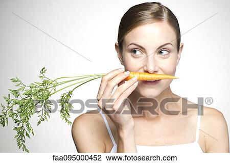 Young woman smelling carrot View Large Photo Image Stock Image - Young woman smelling carrot. Fotosearch