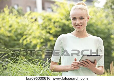 Stock Photograph - Young woman using digital tablet outdoors. Fotosearch