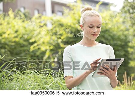 Stock Photography - Young woman using digital tablet outdoors. Fotosearch