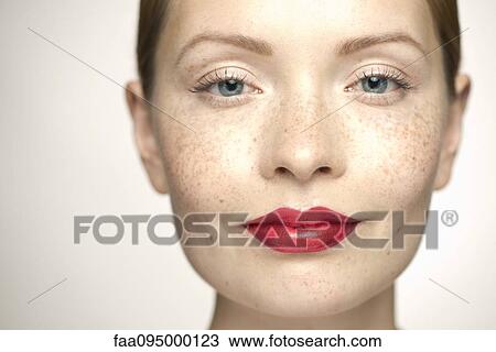 Stock Image - Young woman wearing bright red lipstick, portrait. Fotosearch