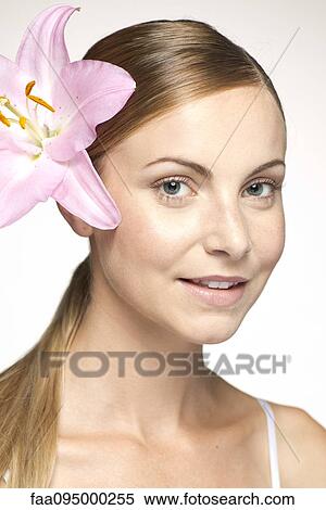 Young woman wearing lily in hair, portraitwearing View Large Photo Image Stock Photography - Young woman wearing lily in hair, portraitwearing. Fotosearch