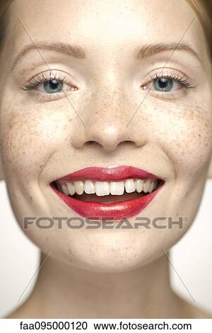 Stock Image - Young woman wearing red lipstick, smiling, portrait. Fotosearch