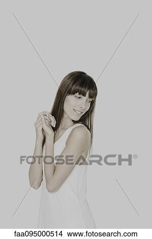 Young woman with hands clasped, looking over shoulder, smiling View Large Photo Image Picture - Young woman with hands clasped, looking over shoulder, smiling. Fotosearch